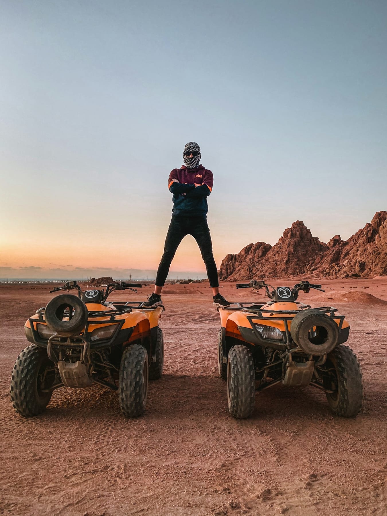 Man balancing on two quad bikes in the Egyptian desert